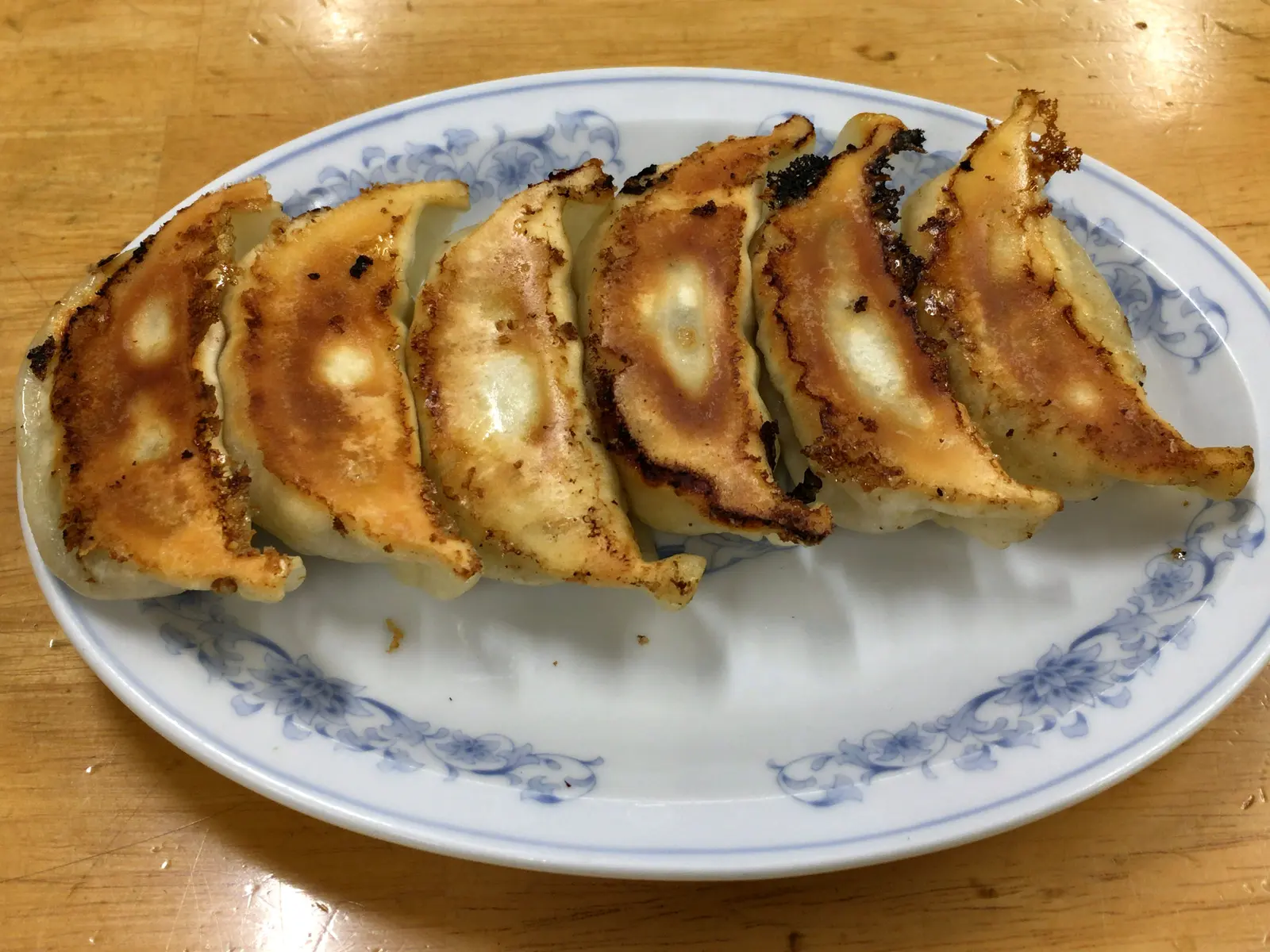 Empanadillas doradas a la plancha en fila sobre un plato de borde azul
